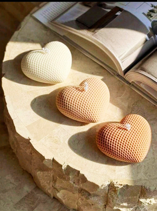 Bougie cœur texturé en forme de cœur, artisanale, avec une élégante texture, sur une table décorative.