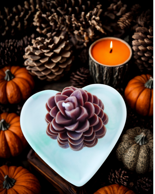 Bougie pomme de pin artisanale décorative au centre, entourée de pommes de pin et de citrouilles sur fond automnal.