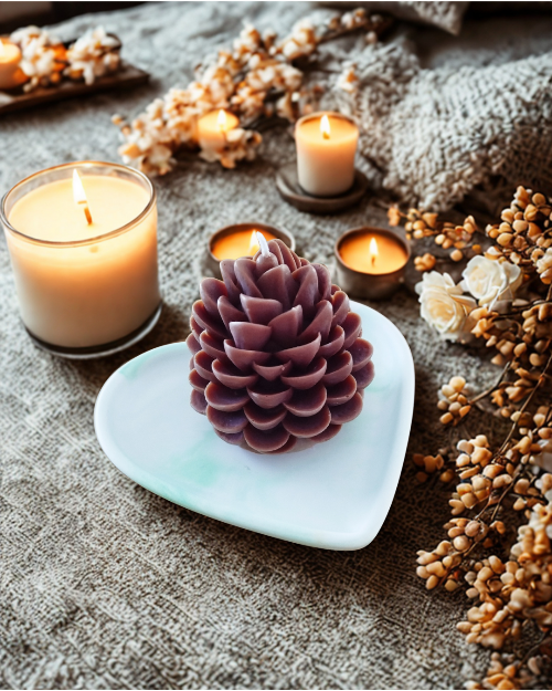 Bougie pomme de pin sur un plateau en forme de cœur avec des bougies et des fleurs décoratives.