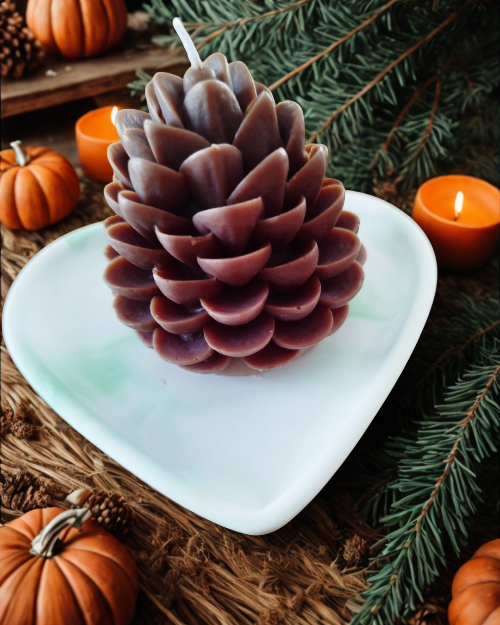 Bougie pomme de pin sur un plateau en forme de cœur, décorée avec des citrouilles et des bougies allumées.