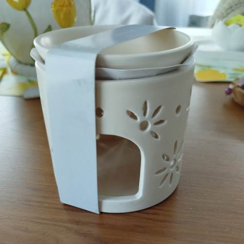 Détail du brûleur à fondants parfumés montrant le motif de fleurs ajourées en céramique élégante.