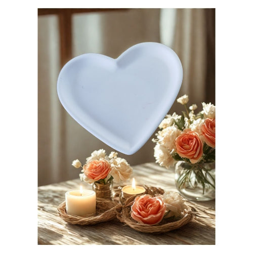 Aphrodite - Coupelle Cœur en Minéral Marbrée en forme de cœur blanc avec des fleurs et des bougies en arrière-plan.
