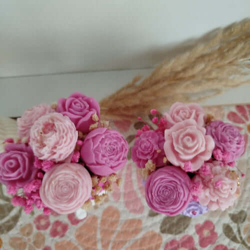Gros plan sur les fleurs en cire rose et violette, aux formes de roses et gypsophiles, sur les têtes en pierre minérale blanche.