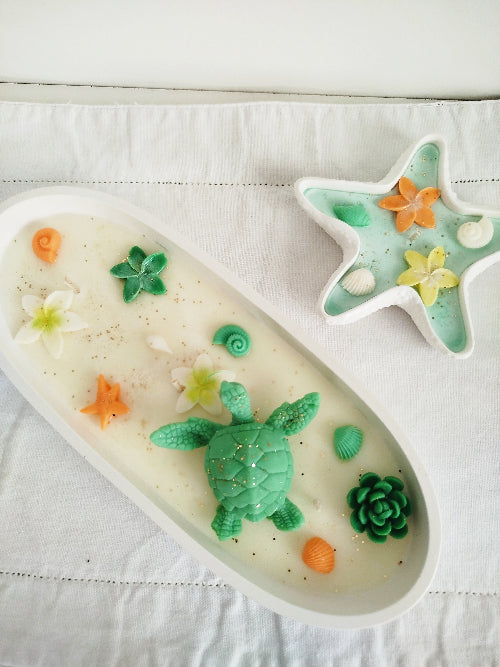 Décor de fleurs blanches, étoiles de mer et coquillages en cire parfumée.