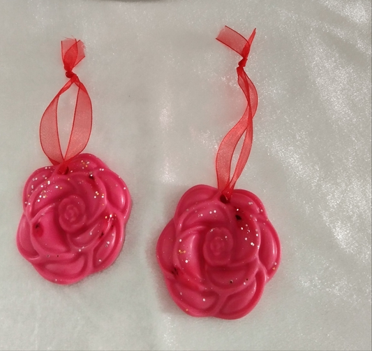 Suspension parfumée artisanale en forme de rose rose, ornée de paillettes et de rubans rouges.