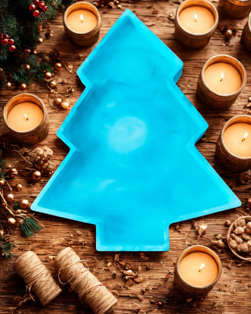 Décoration Sapin – Élégance et Magie de Noël, un plat en forme de sapin bleu entouré de bougies et décorations de Noël.