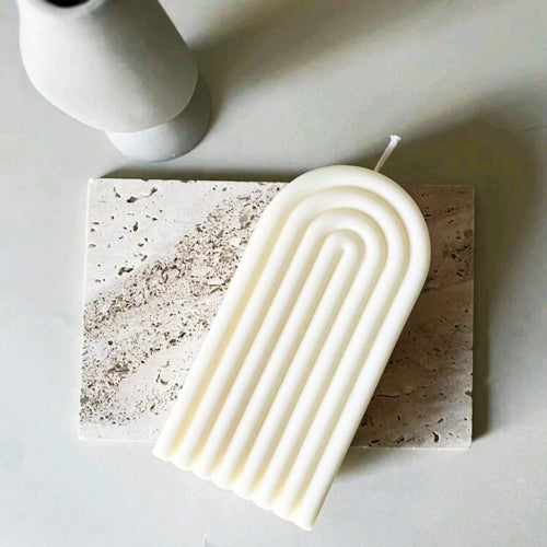 Bougie en Arche parfumée sur un support en pierre, mettant en valeur son design élégant et moderne.