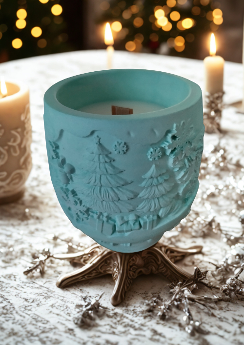 Bougie parfumé Forêt Enchantée en céramique turquoise, décorée de motifs de sapins, sur une table de fête.