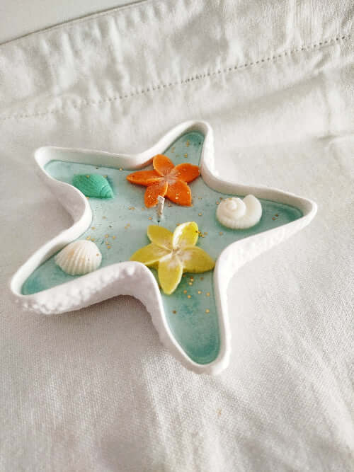 Bougie décorative tropicale dans un contenant minéral en forme d’étoile.