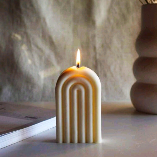 Une bougie décorative en cire naturelle allumée, posée sur une table, avec un design en arc élégant.