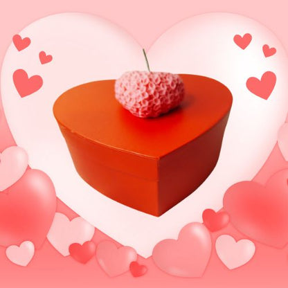 Bougie en forme de cœur sculptée  entourée d'un fond rose de petits cœurs, évoquant une ambiance douce et romantique