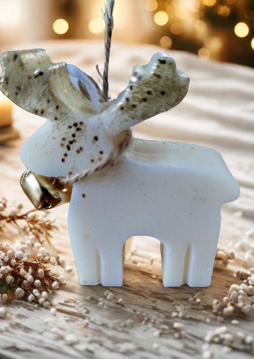 Bougie de Noël cerf parfumée artisanale allumée parmi des bougies et décorations naturelles.