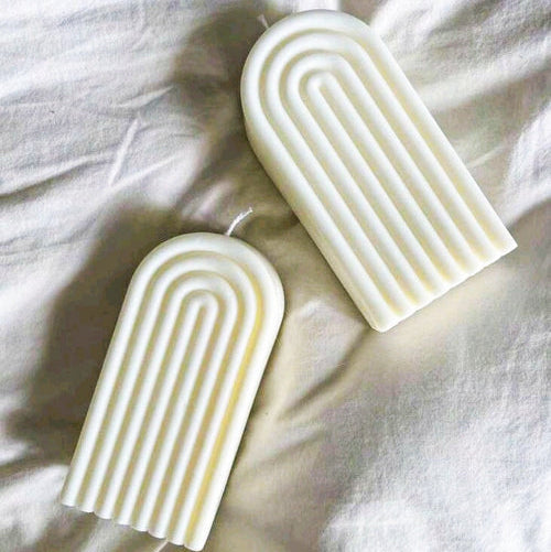 bougies modernes en cire naturelle, avec des détails dorés, posées sur un tissu élégant.