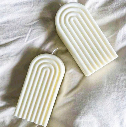 bougies modernes en cire naturelle, avec des détails dorés, posées sur un tissu élégant.