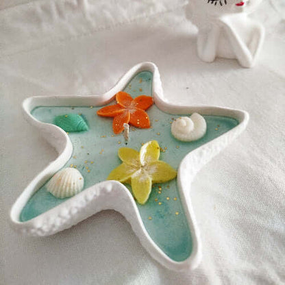Zoom sur les décorations florales et les coquillages incrustés dans la cire bleutée.