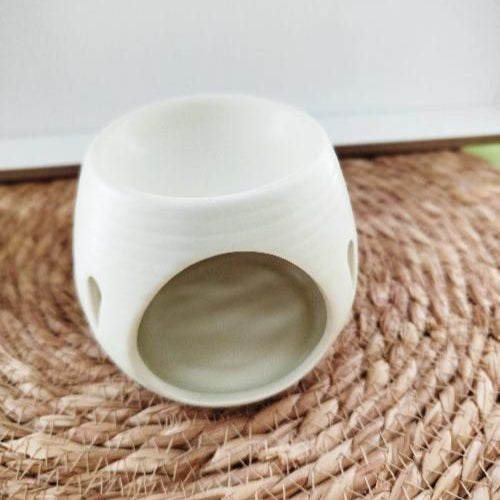 Brûleur en céramique avec motifs gouttes, placé dans une ambiance zen et naturelle.