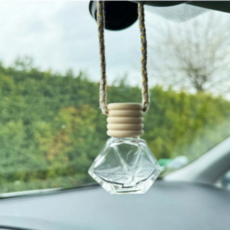Diffuseur de voiture suspendu au rétroviseur avec un flacon en verre et un bouchon en bois.