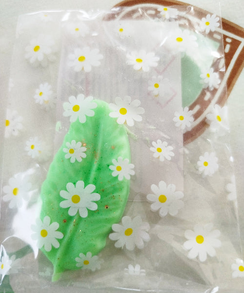 LOT DE 10 FONDANTS PARFUMES AUX SENTEURS VARIEES, présentation d'un fondant parfumé en forme de feuille verte dans un sachet fleuri.