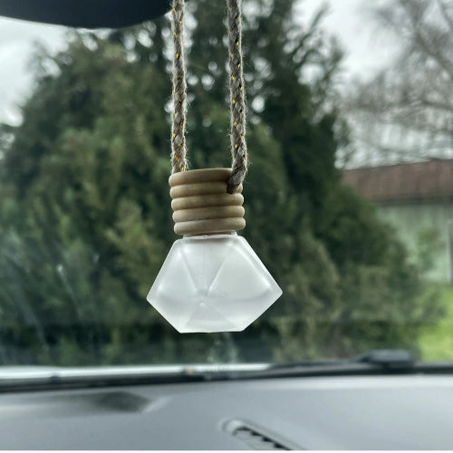 Plusieurs diffuseurs en verre avec des bouchons en bois et des cordons torsadés, posés sur un tissu.