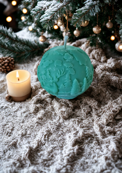 Bougies -Boules de Noël parfumées artisanales, l’une verte avec motifs de sapins et l’autre blanche pailletée, disposées parmi des décorations de fête rustiques.