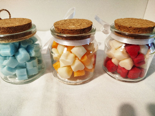 Pot en verre avec bouchon en liège et mini fondants parfumés dans une mise en scène décorative.