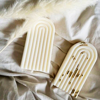 Gros plan d'une bougie blanche minimaliste en cire naturelle avec un design en relief d'arc.